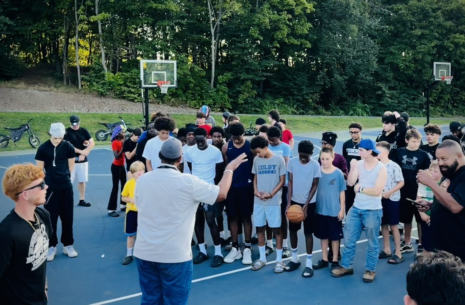 Shifting Gears founder huddling with local kids on the basketball court